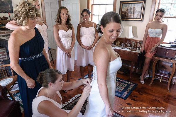 Bride getting ready, attendants looking on.