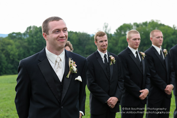 Groom at wedding ceremony smiles as he sees his bride