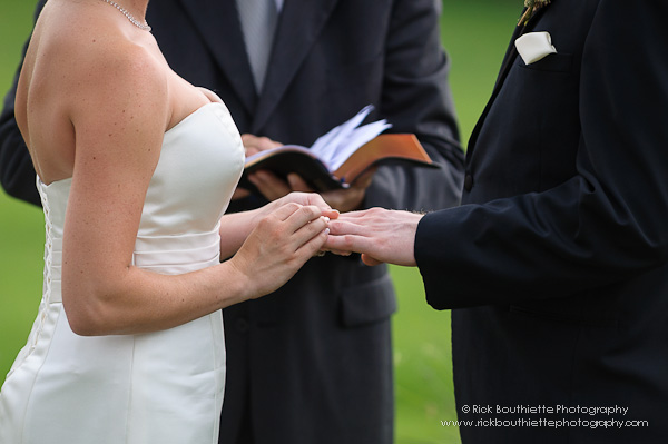 Bride slips ring on Groom's finger at wedding ceremony