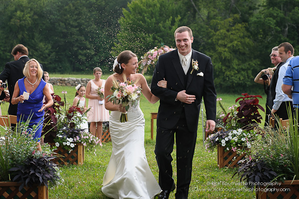 Bride & groom walking down aisle at wedding ceremony, grass seed thrown