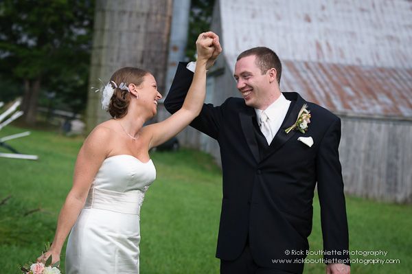 Bride & Groom smiling, dancing in field, barn in background