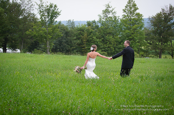 Bride & Groom walking through hay field holding hands