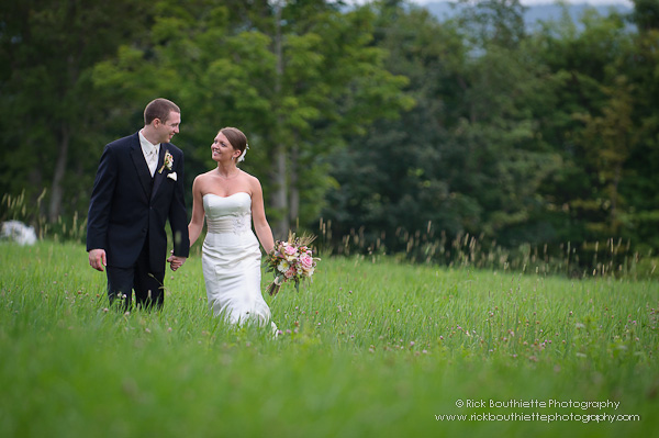 Bride & Groom walking through hay field holding hands smiling at each other