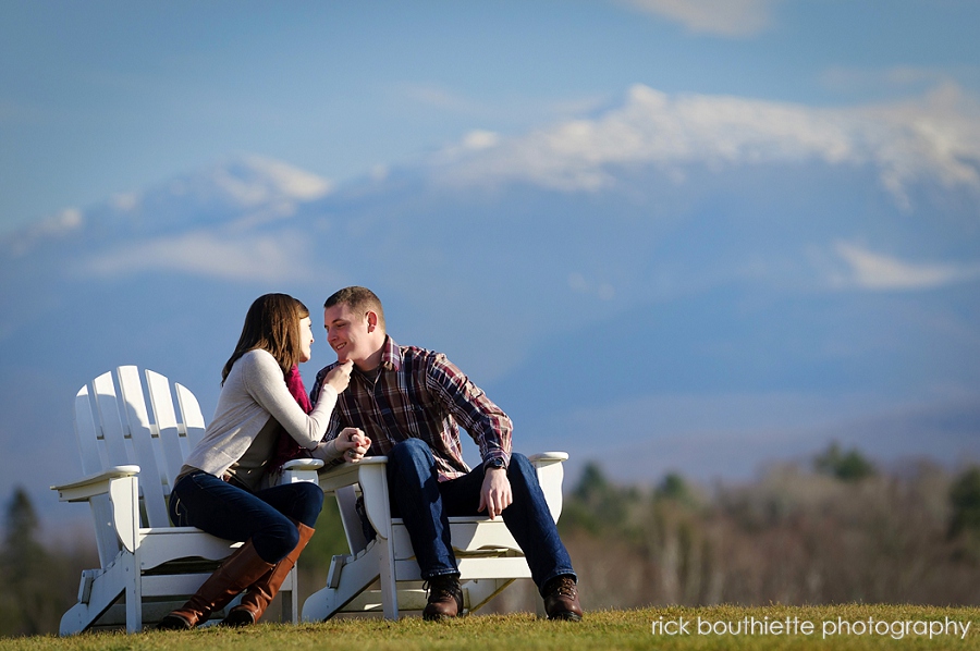 couple sitting in Adirondack chairs on hill with mountains in the background
