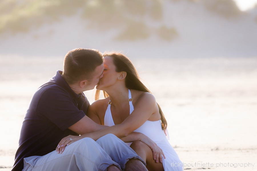 couple kissing on beach during engagement photo session