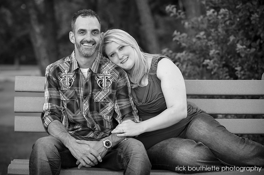 couple sitting on bench at engagement photo session in B&W