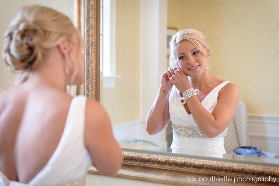 gorgeous bride in mirror putting earring on