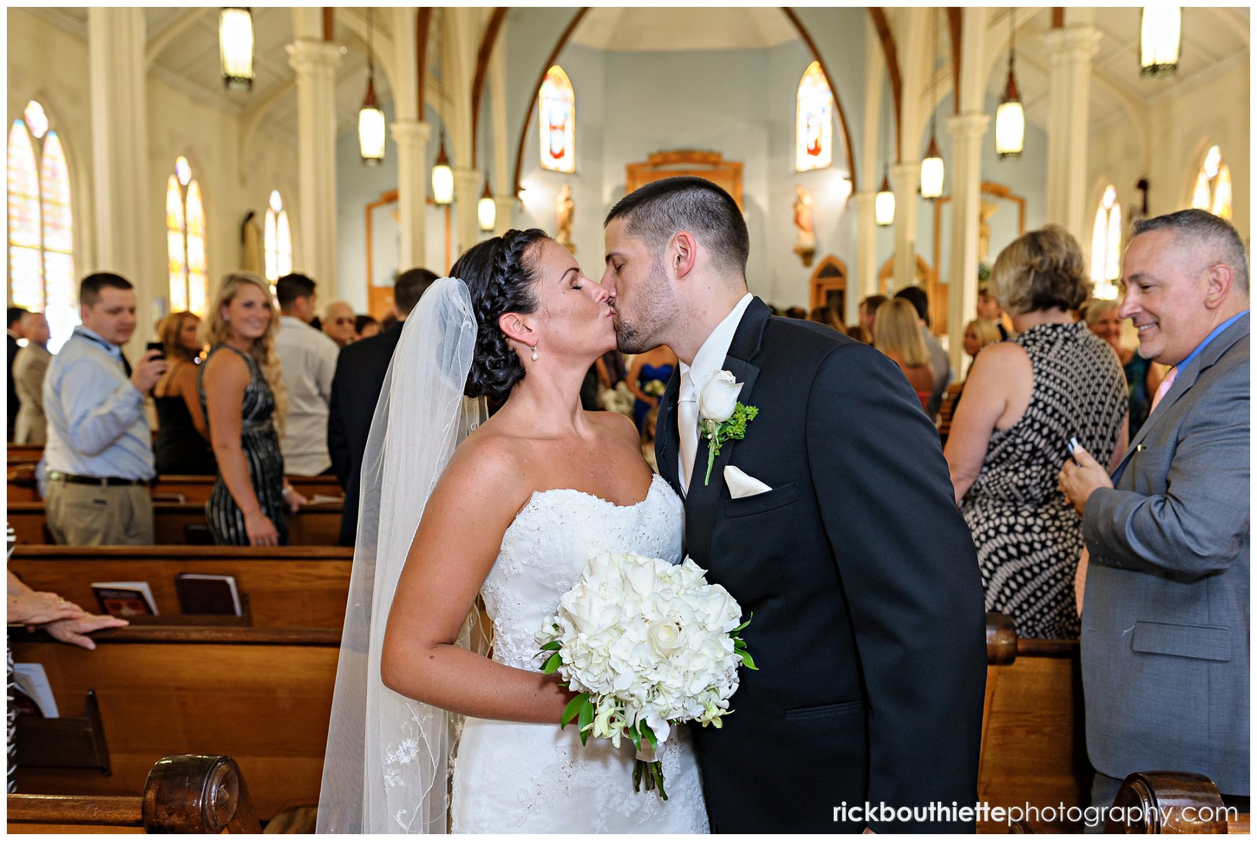 bride and groom kissing at back of church