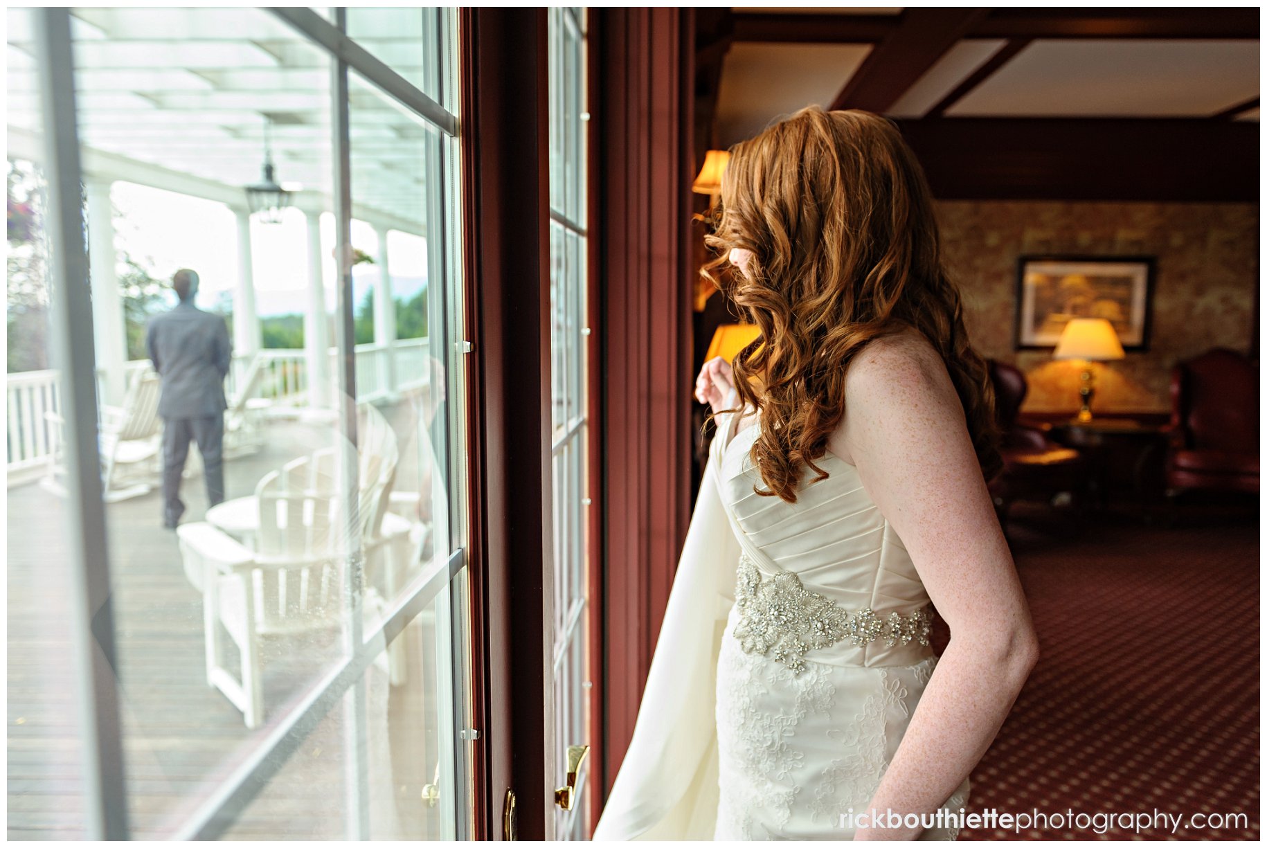 bride peeking out onto veranda where groom awaits her
