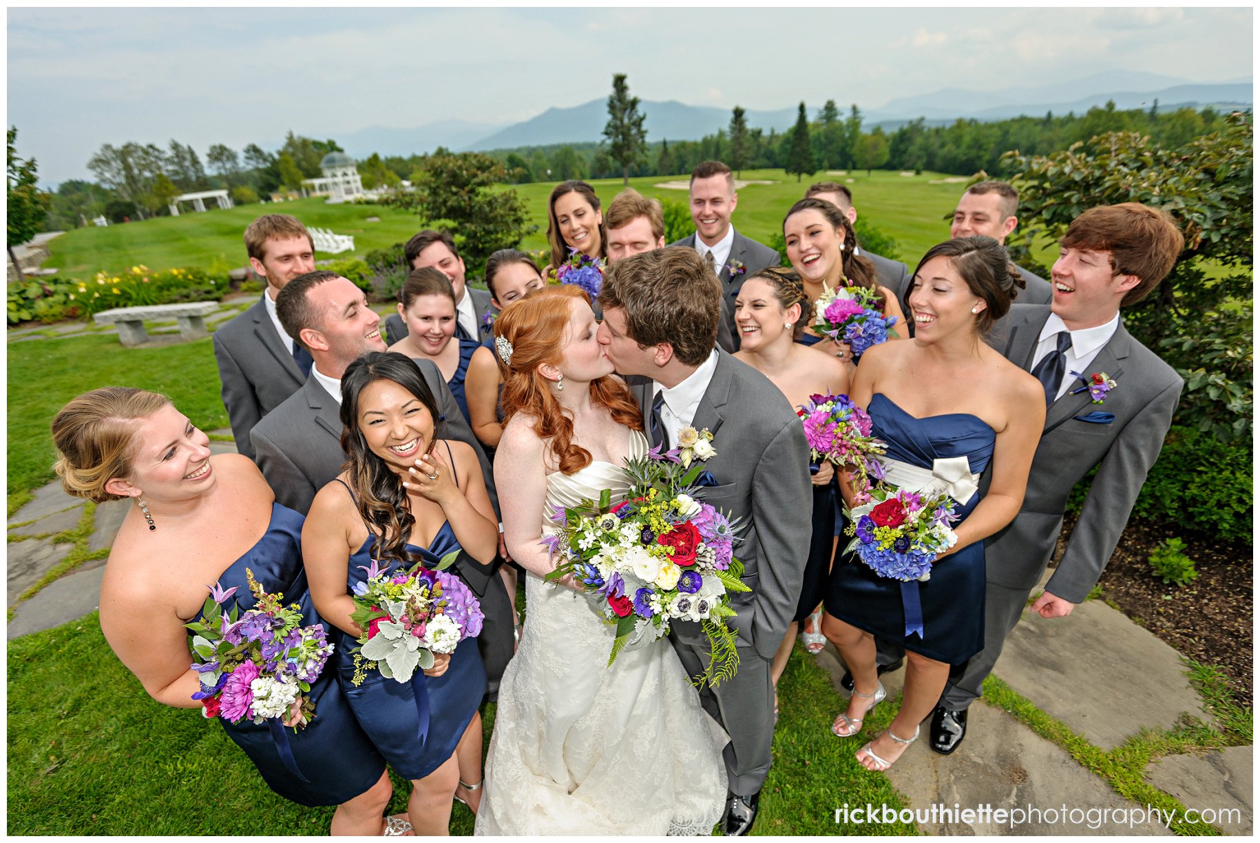 Bride and groom enjoy a kiss as the wedding party cheers them on