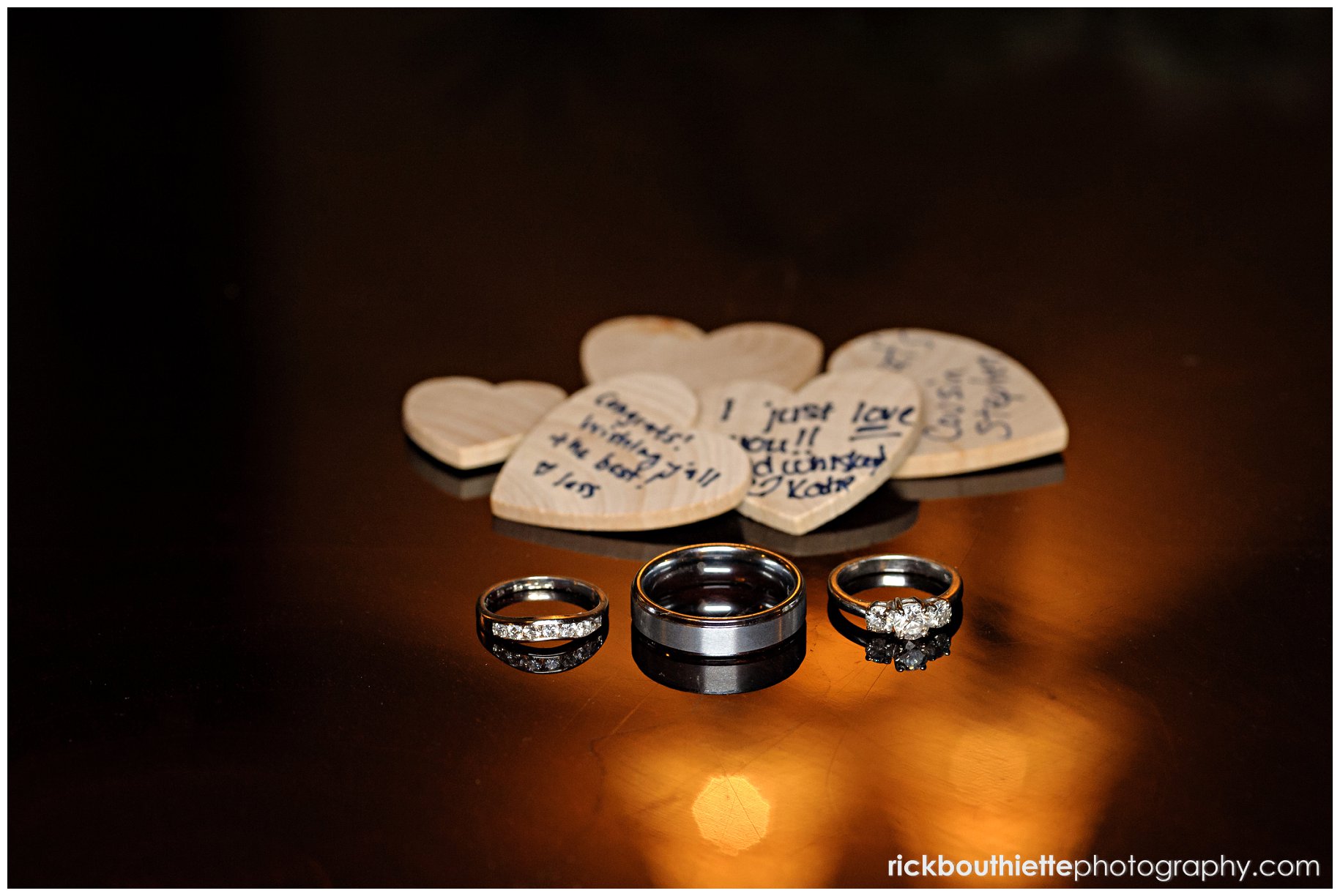 wedding rings in warm light with wooden hearts in background