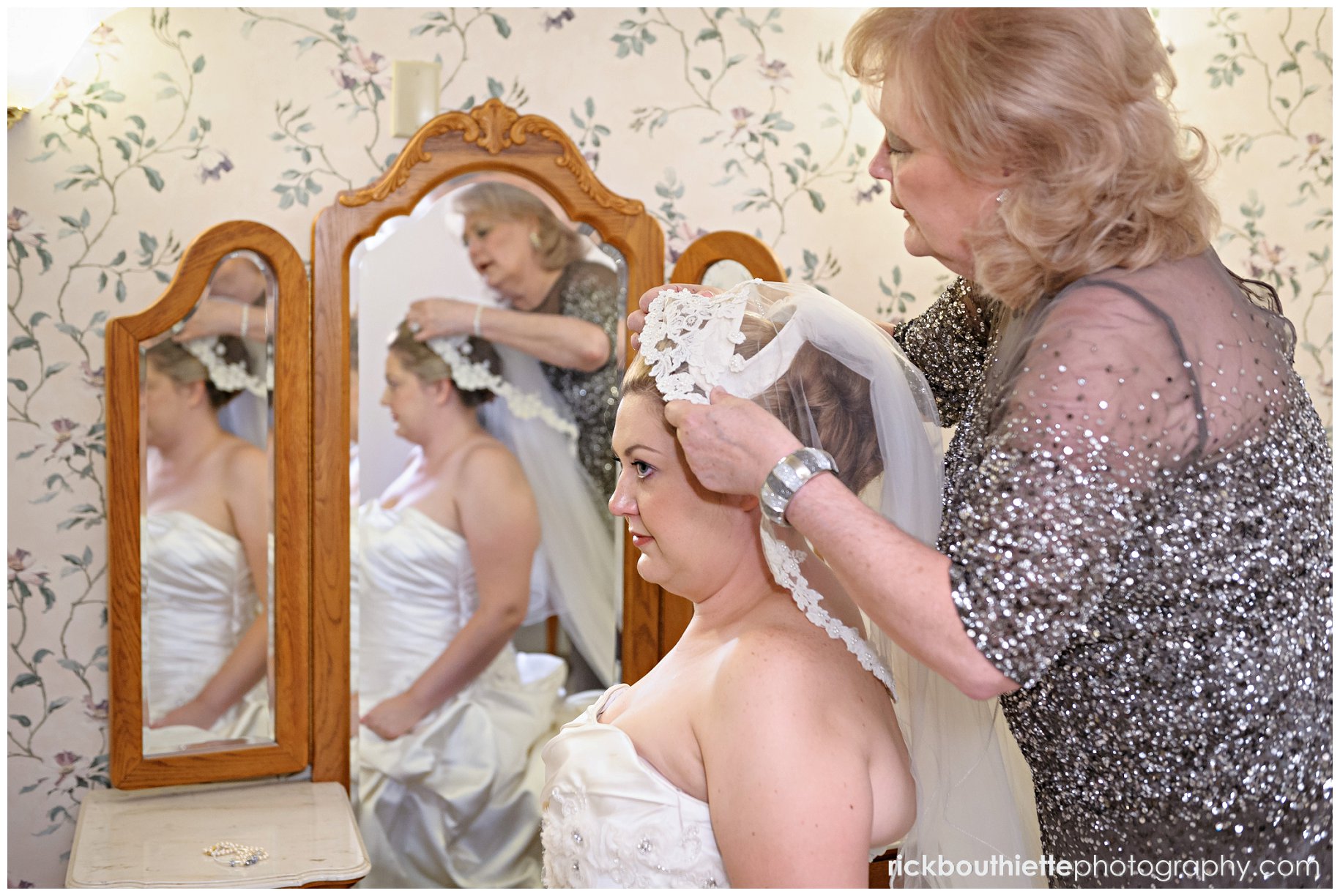 mother of the bride puts veil on bride