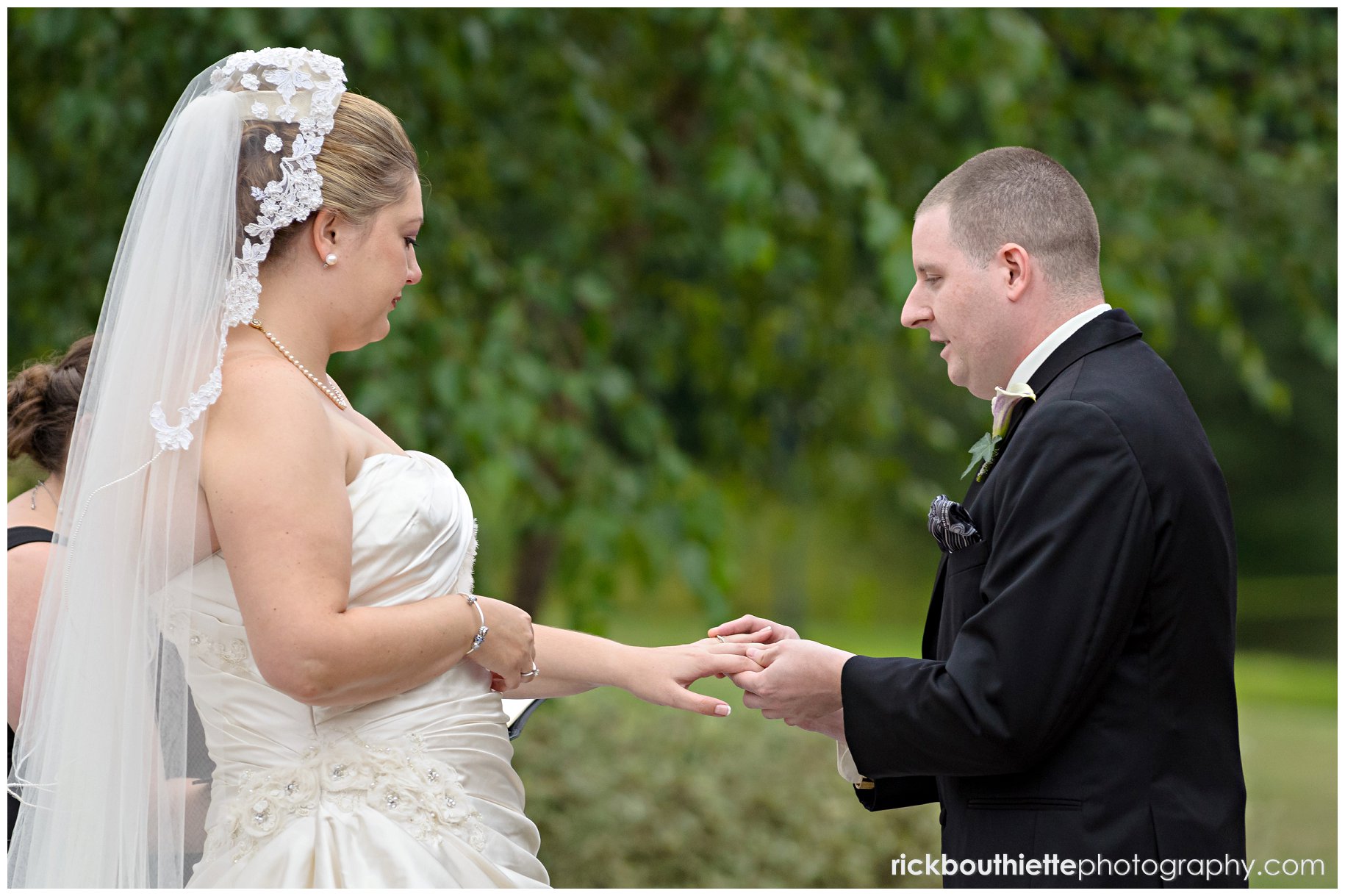 groom placing ring on bride's finger at wedding ceremony