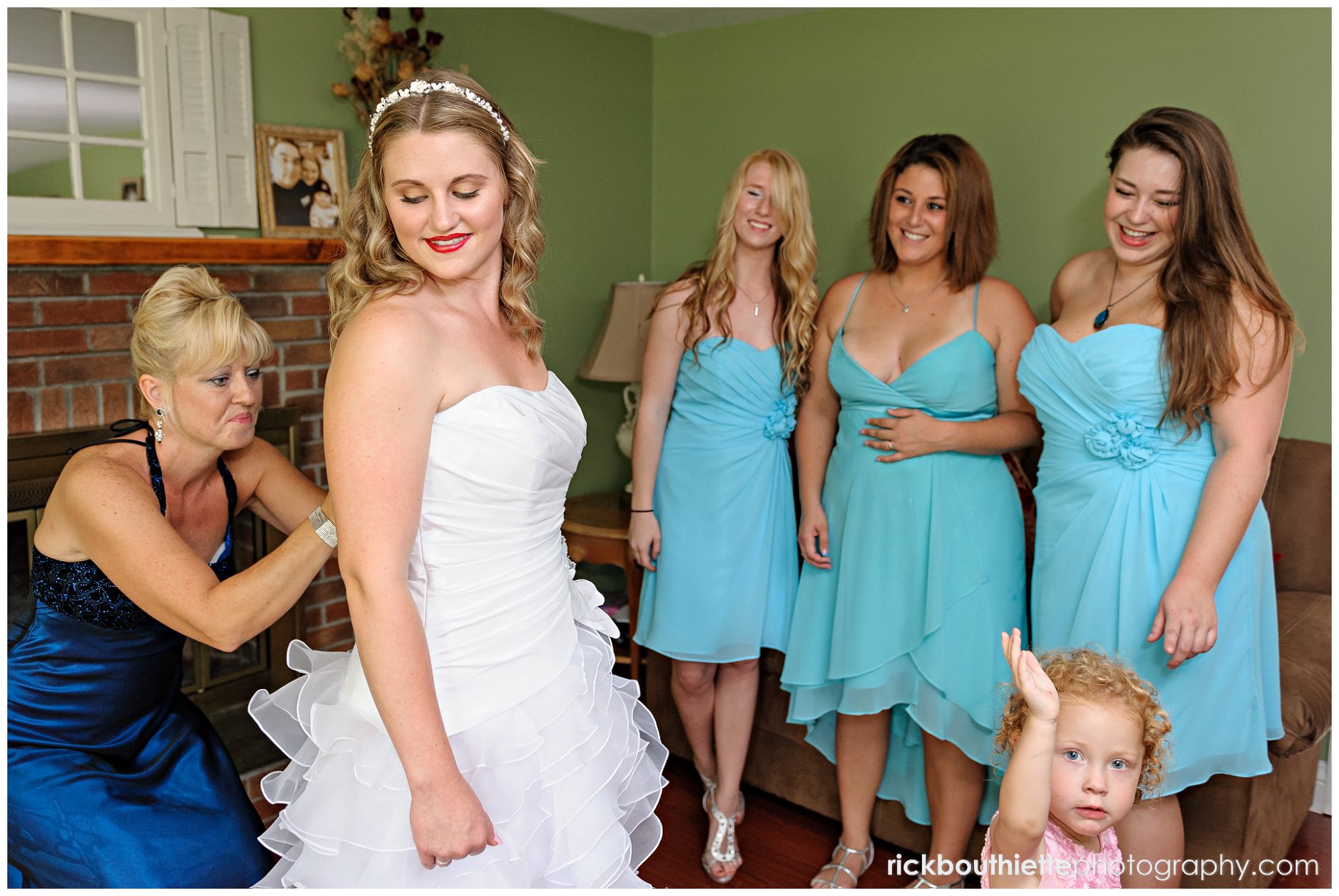 Mother of the bride helps bride with wedding dress, bridesmaids looking on at New Hampshire seacoast wedding