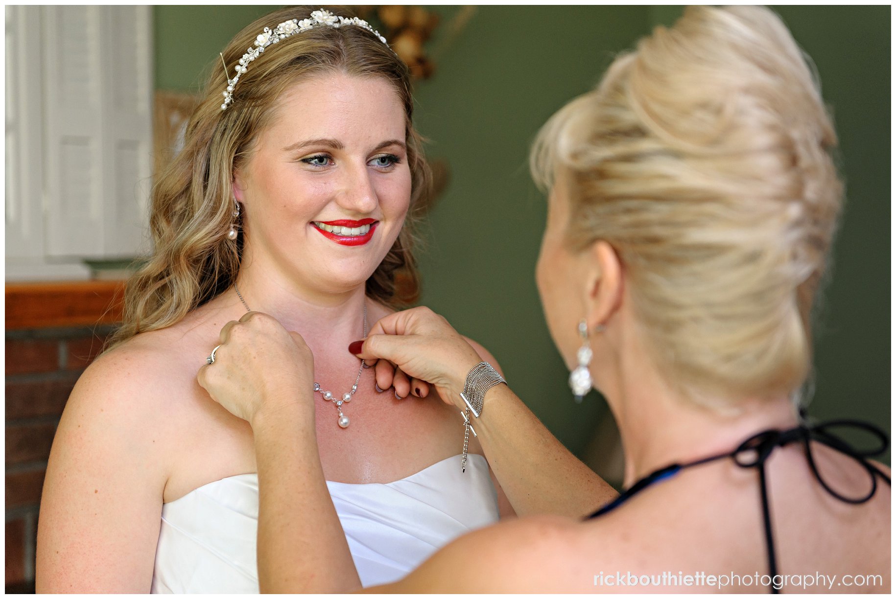 Mother of the bride adjusts bride's necklace