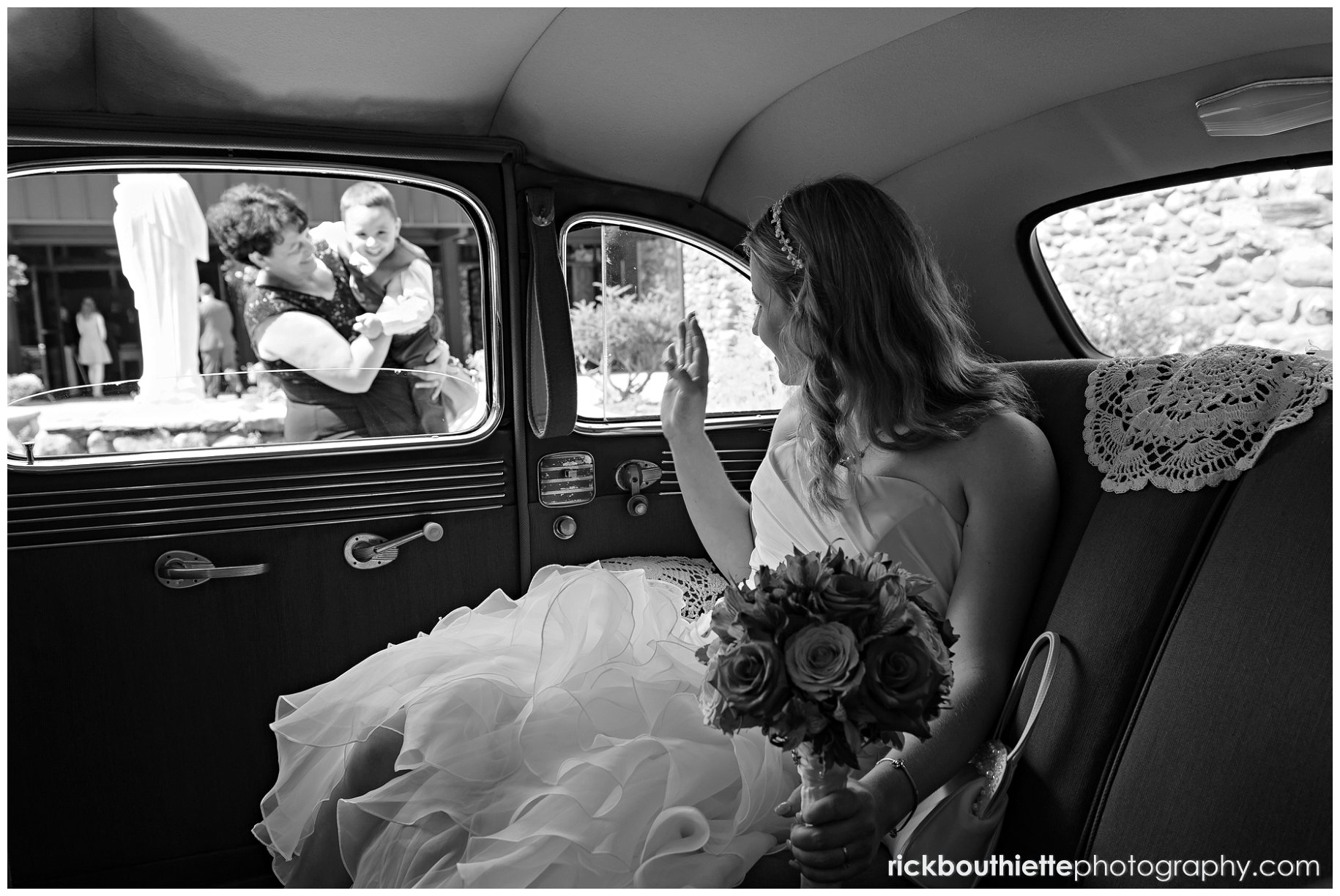 Bride in antique car waving to her son through window