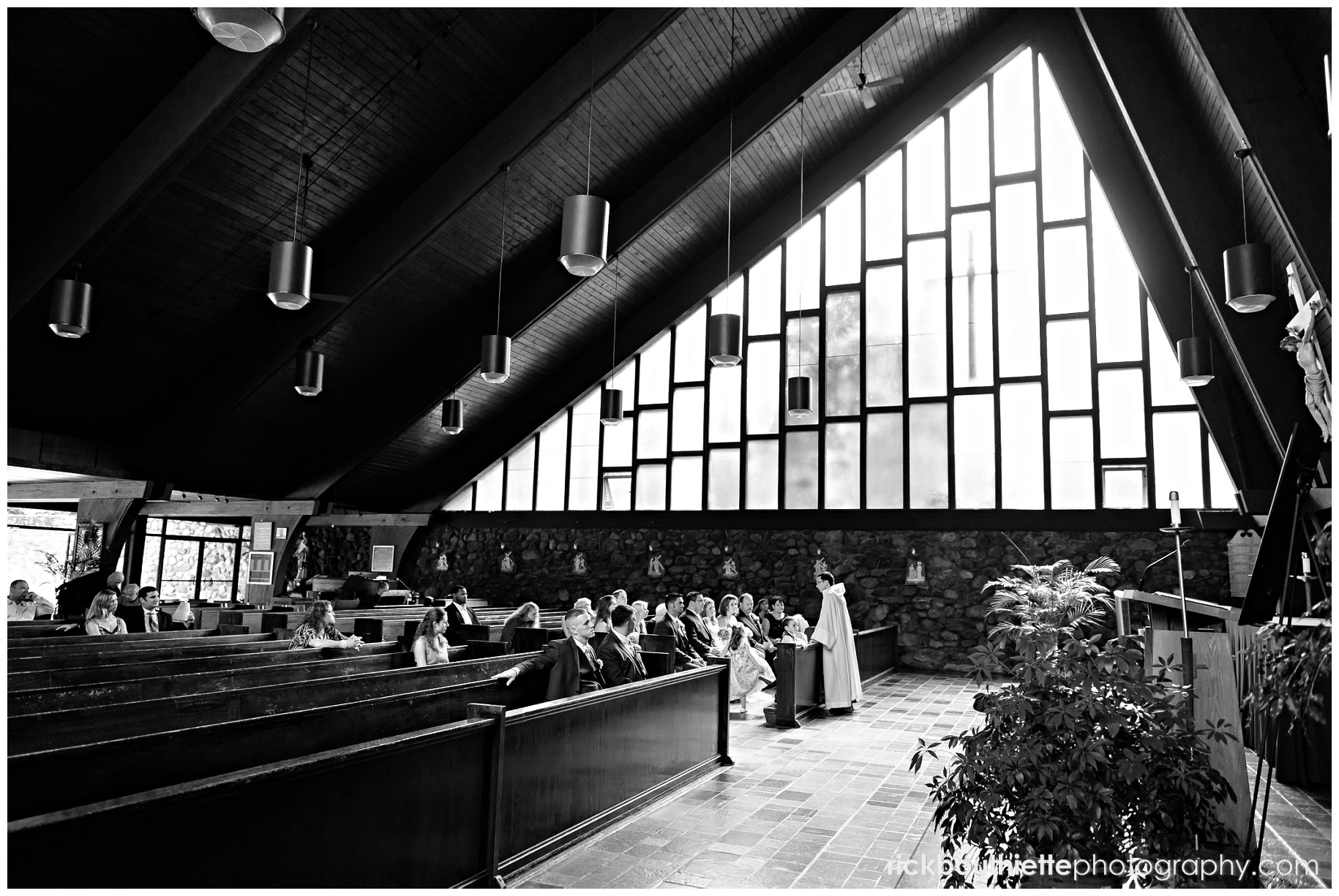 Overall view of geometrically interesting church during wedding ceremony, black & white