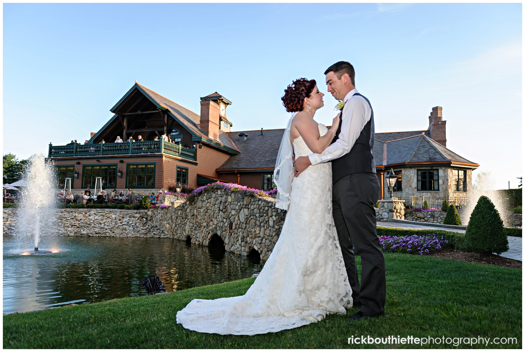 bride & groom embrace with Tewksbury Country Club in the background