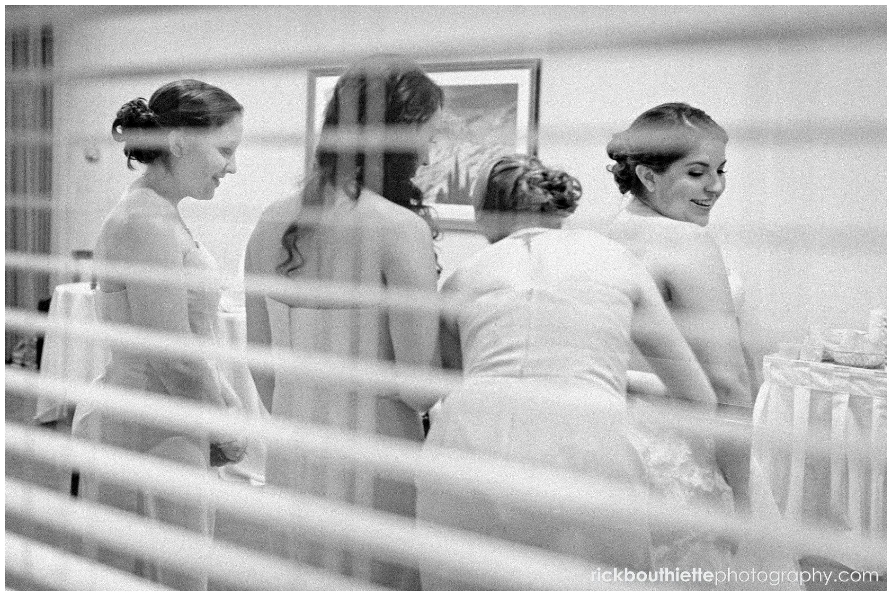 bride & bridesmaids getting ready through window blinds