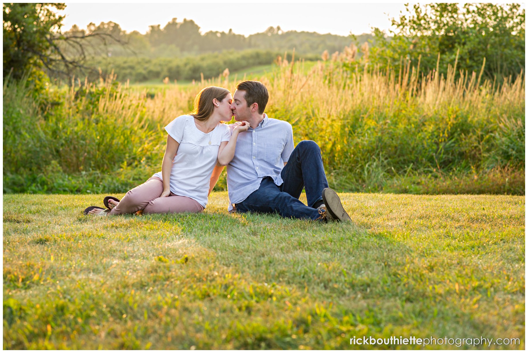 couple kissing in a field just before sunset during engagement session