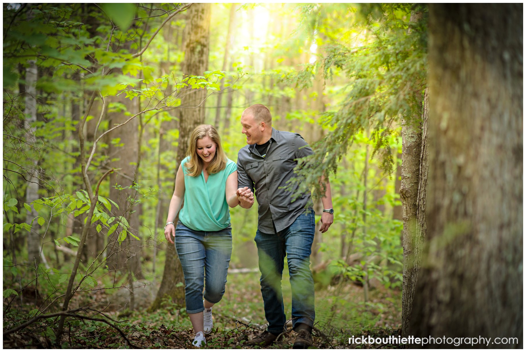 couple walking in the woods with sun flare above them at NH engagement session