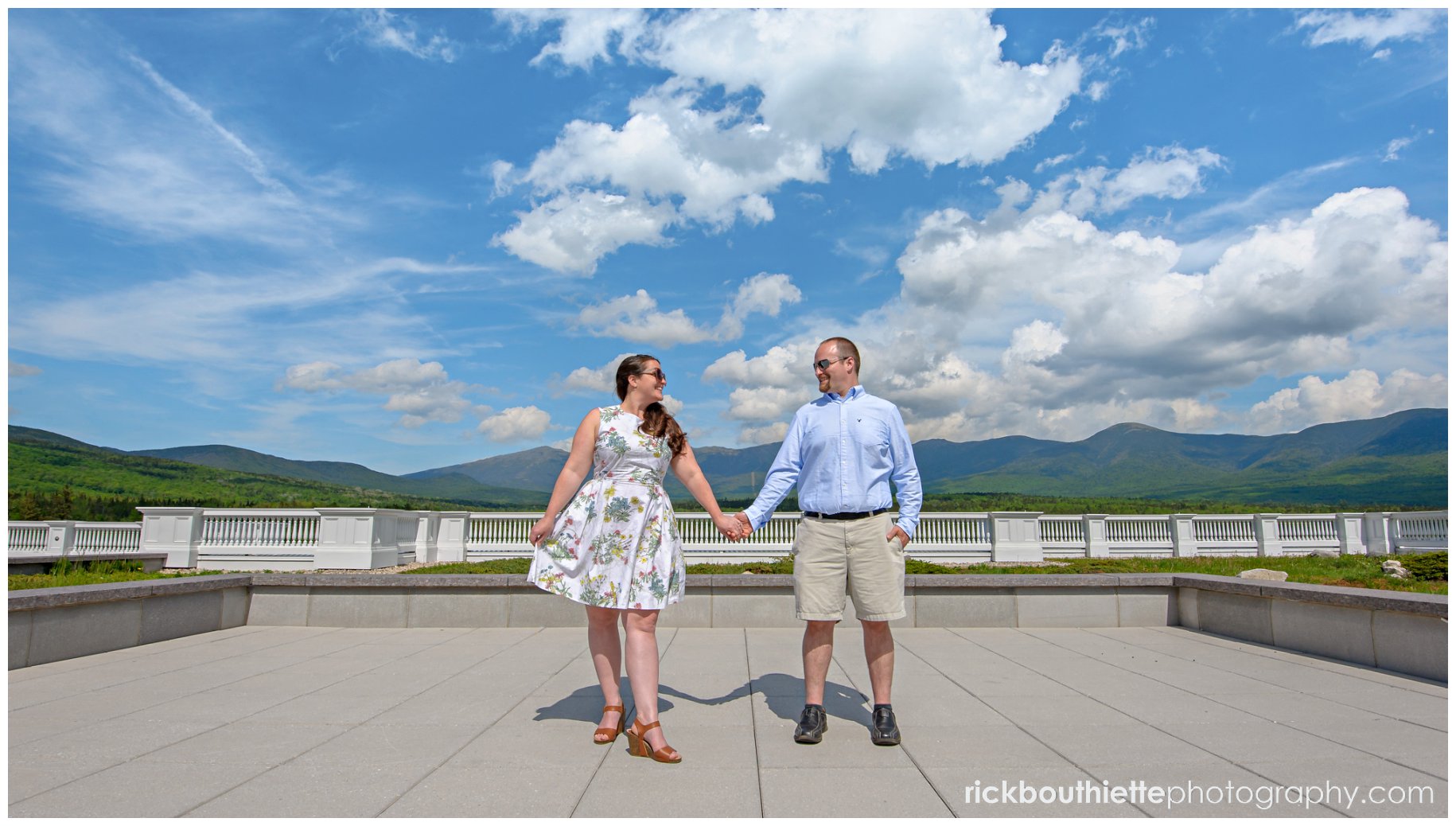 couple holding hands at omni mount washington resort engagement session mountain range in background