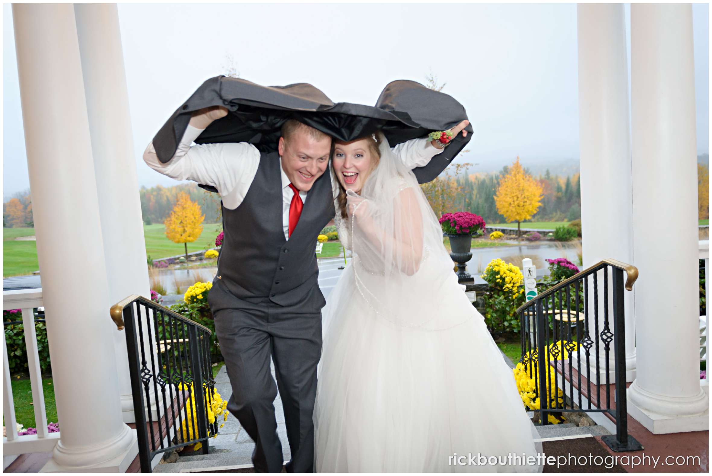 bride and groom running up stairs with jacket overhead in rain