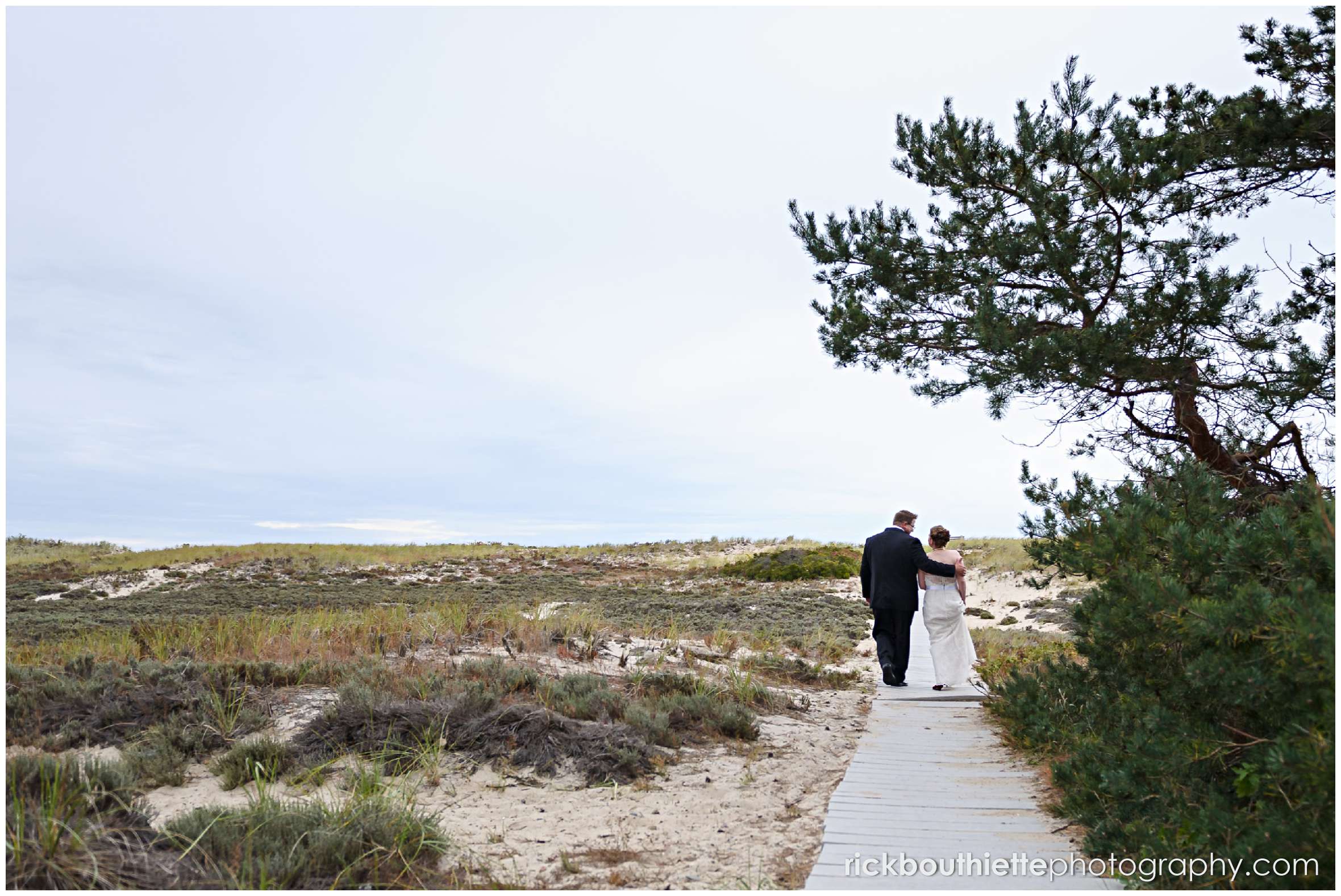 bride and groom walking toward beach on boardwalk at Seabrook NH wedding