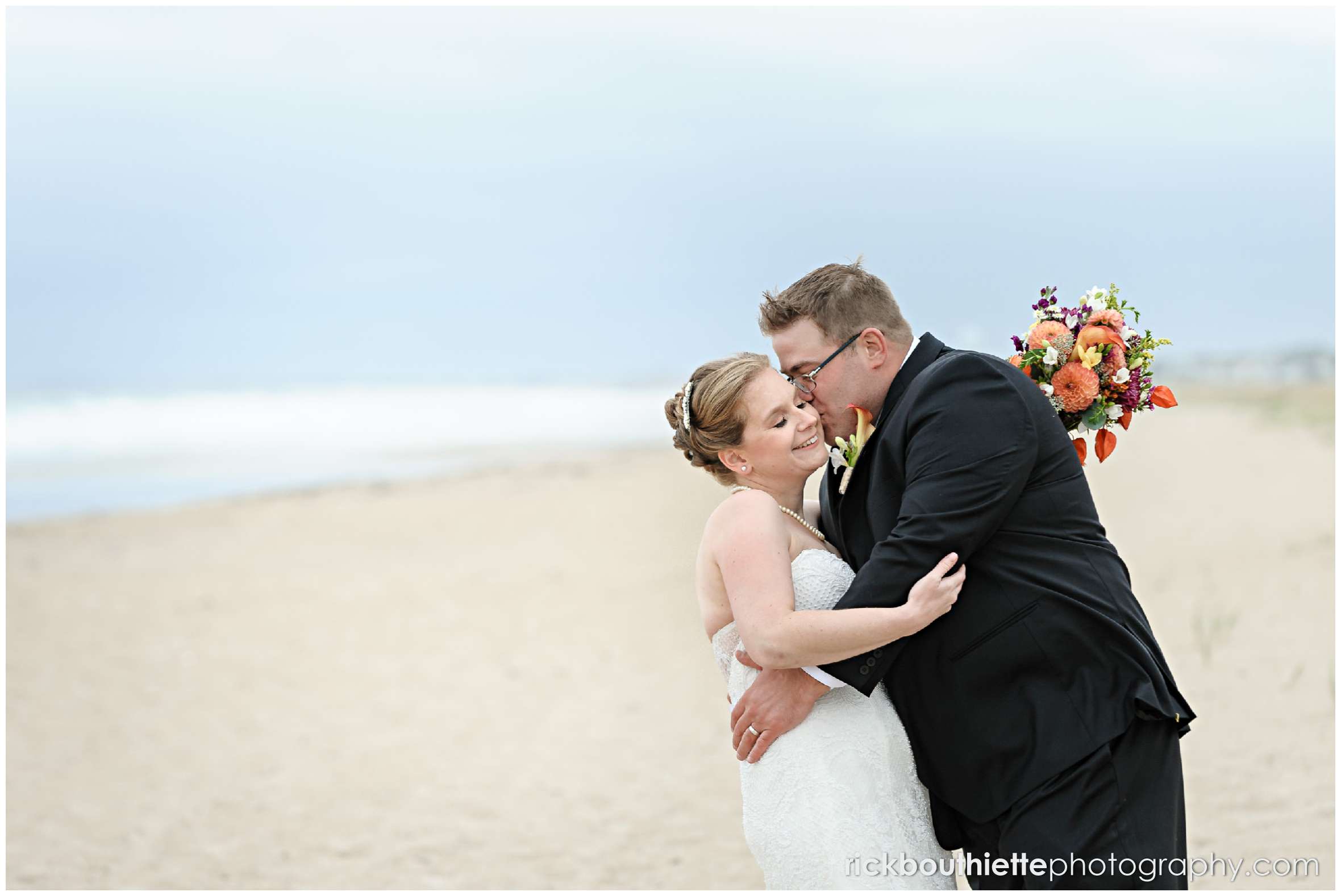 bride and groom kiss on Seabrook beach after their seacoast wedding ceremony