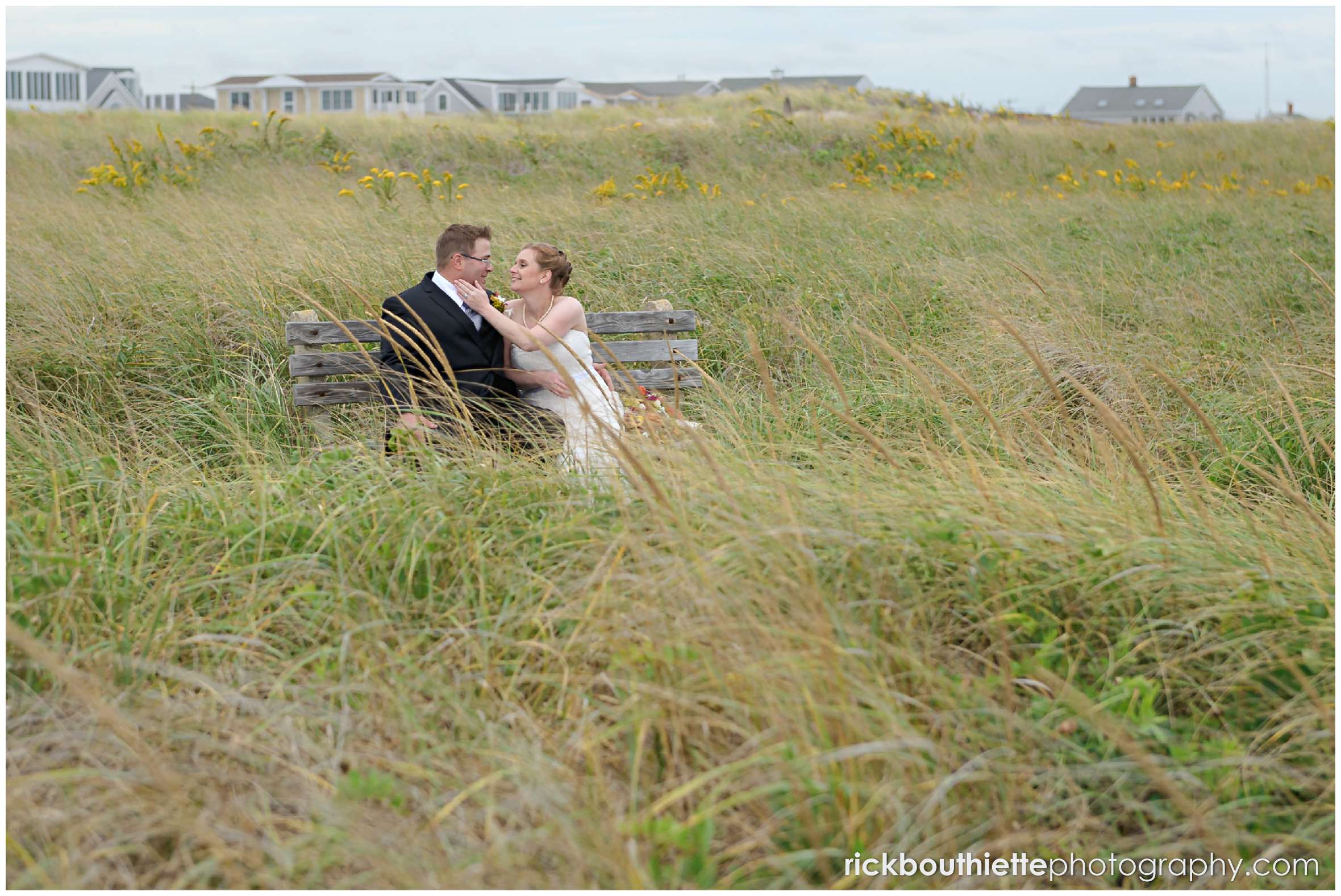 bride and groom sitting on a bench on Seabrook beach after their seacoast wedding ceremony