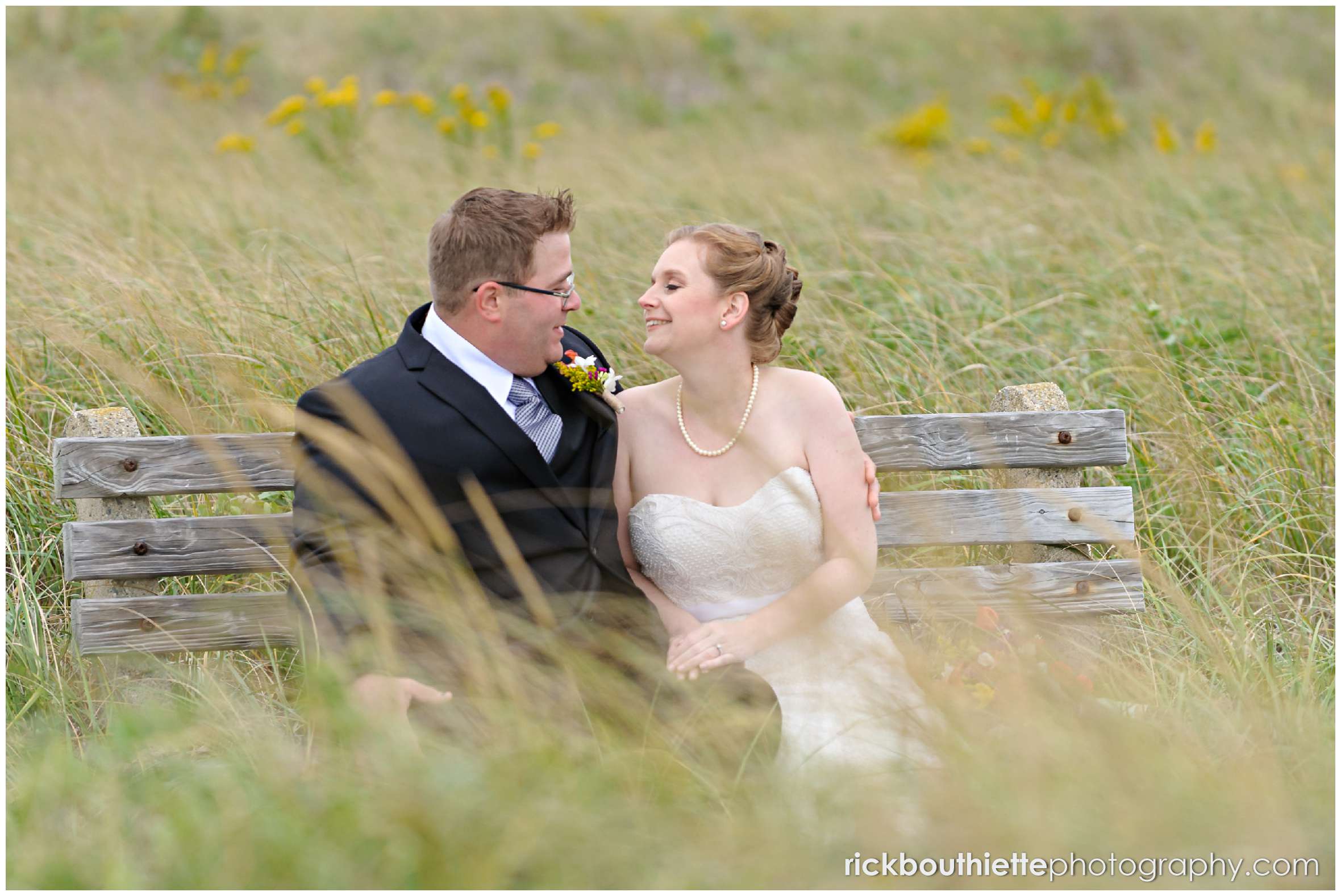 bride and groom sitting on a bench on Seabrook beach after their seacoast wedding ceremony