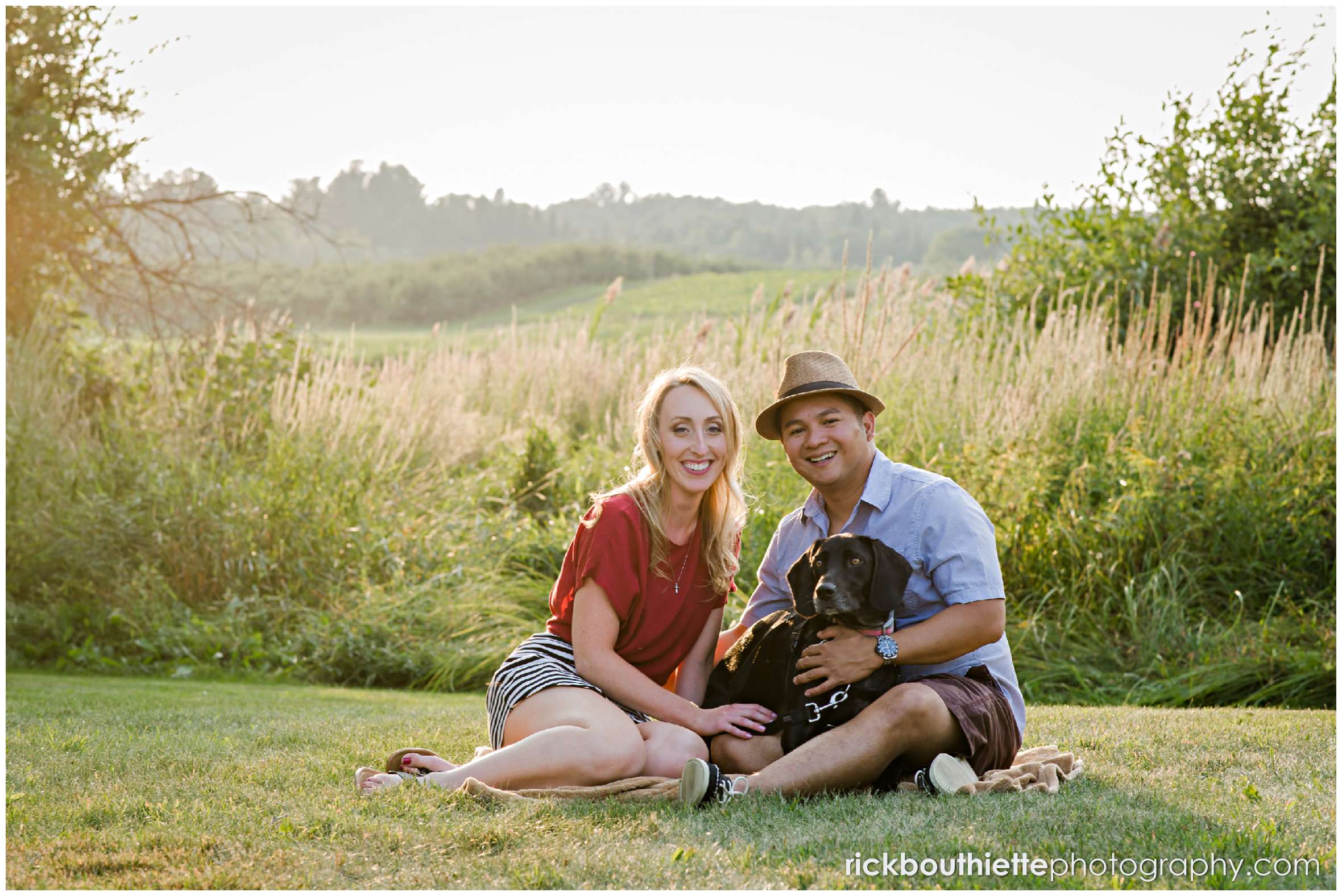 couple sitting with their dog at New Hampshire apple orchard engagement session