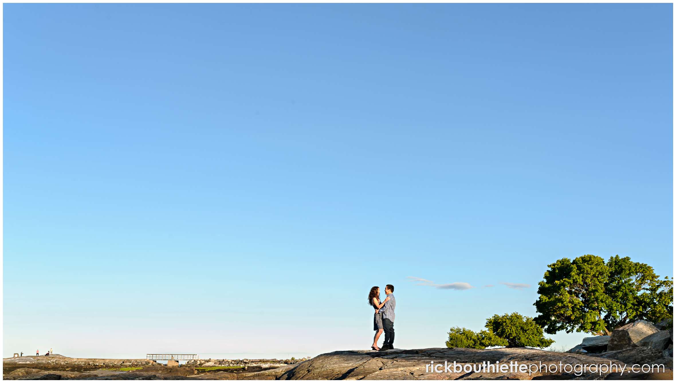 lots of negative space with a couple embracing on the seacoast at their Great Island Common engagement session