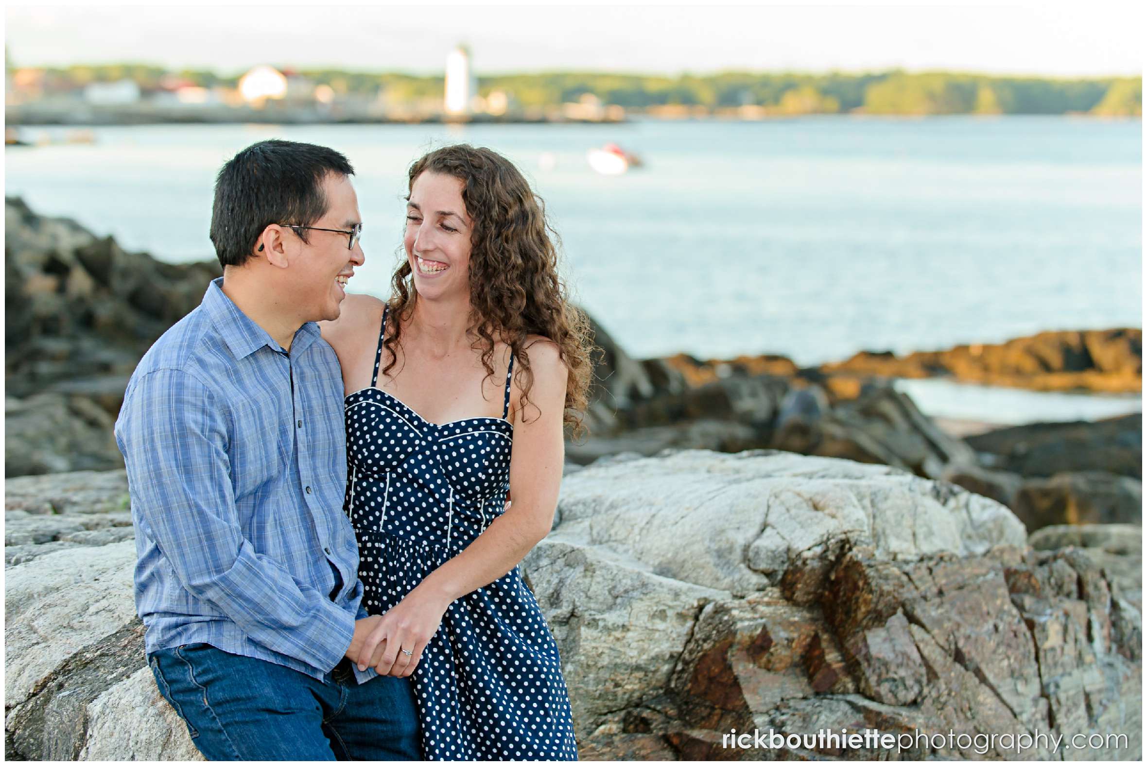 couple sitting on the rocks near the beach at Great Island Common engagement session
