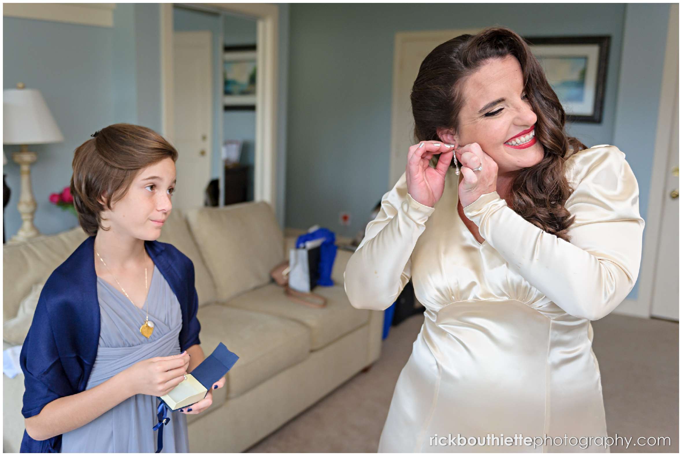 bride putting her earrings on with help of a bridesmaid