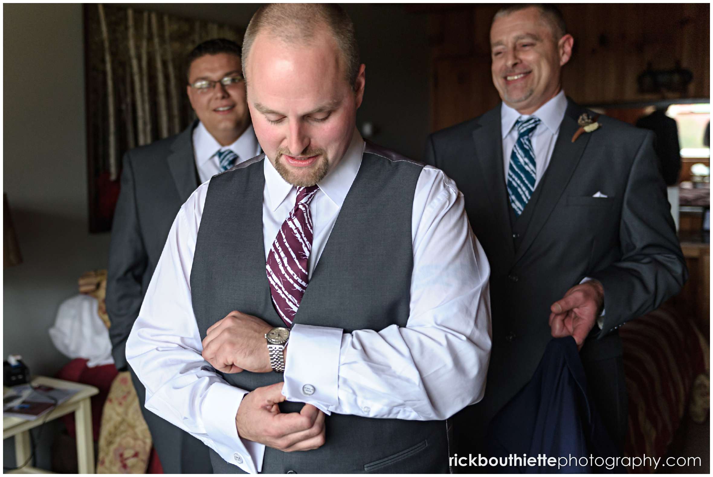 groom adjusting his cuff links with groomsmen looking on as he gets ready for his Snowvillage Inn wedding