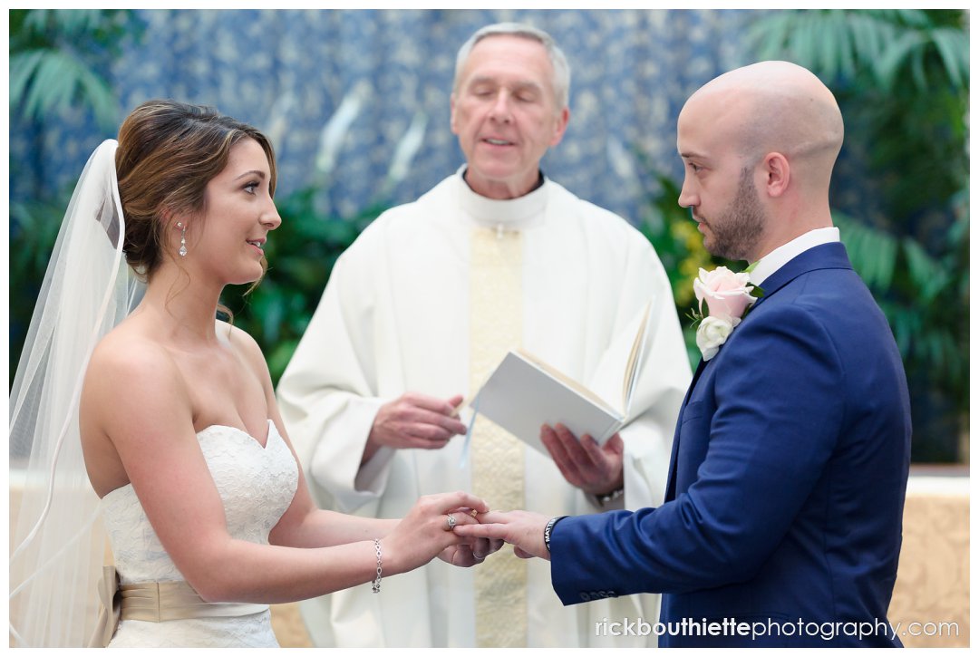 bride and groom exchange rings during their wedding ceremony at Our Lady of Mercy Parish in Merrimack, NH