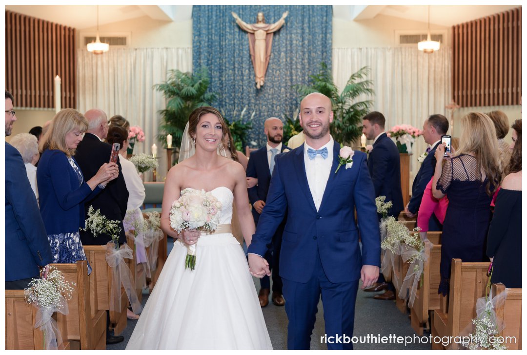bride and groom walking down aisle after their wedding ceremony at Our Lady of Mercy Parish