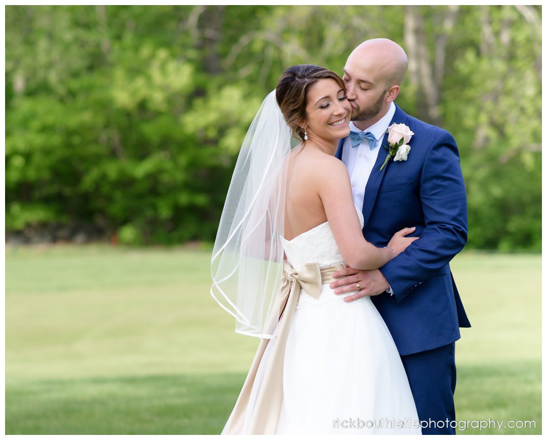 groom kisses his bride on the cheek at Evergreen Pavilion wedding in Southern New Hampshire
