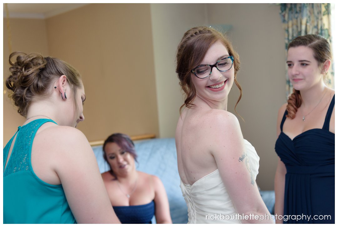 bridesmaids helping bride with finishing touches as she prepares for her wedding