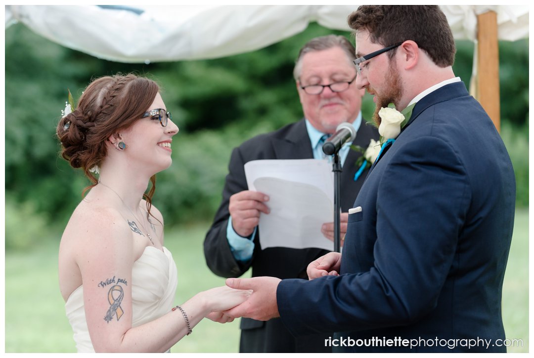 bride and groom exchanging rings at New Hampshire backyard summer wedding