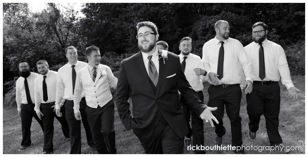 black & white of groom and groomsmen walking at New Hampshire backyard summer wedding