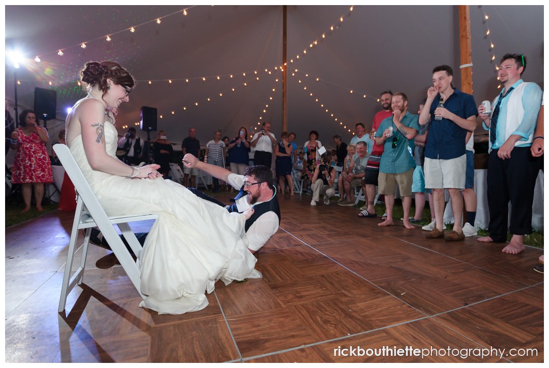 groom getting garter off brides leg at New Hampshire backyard summer wedding reception