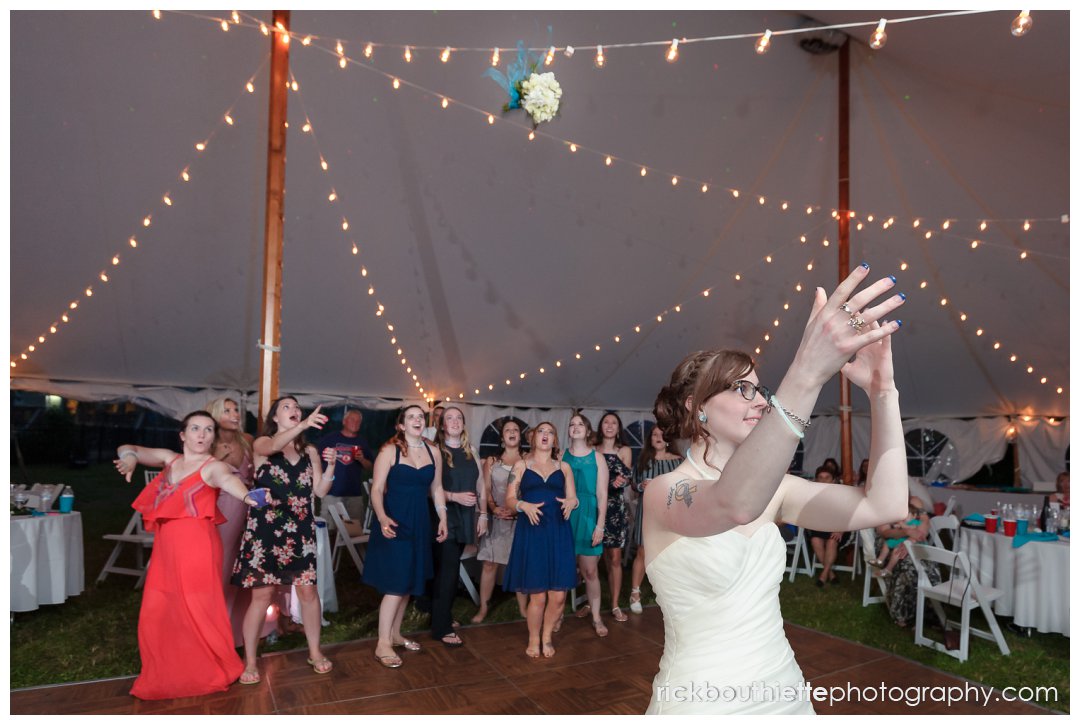 bride throwing the bouquet at New Hampshire backyard summer wedding reception