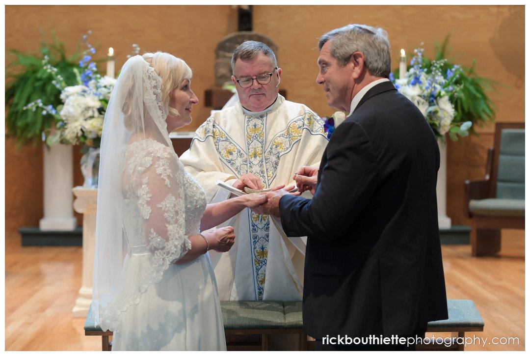 bride and groom exchange rings at ceremony at Saint Joseph's Parish
