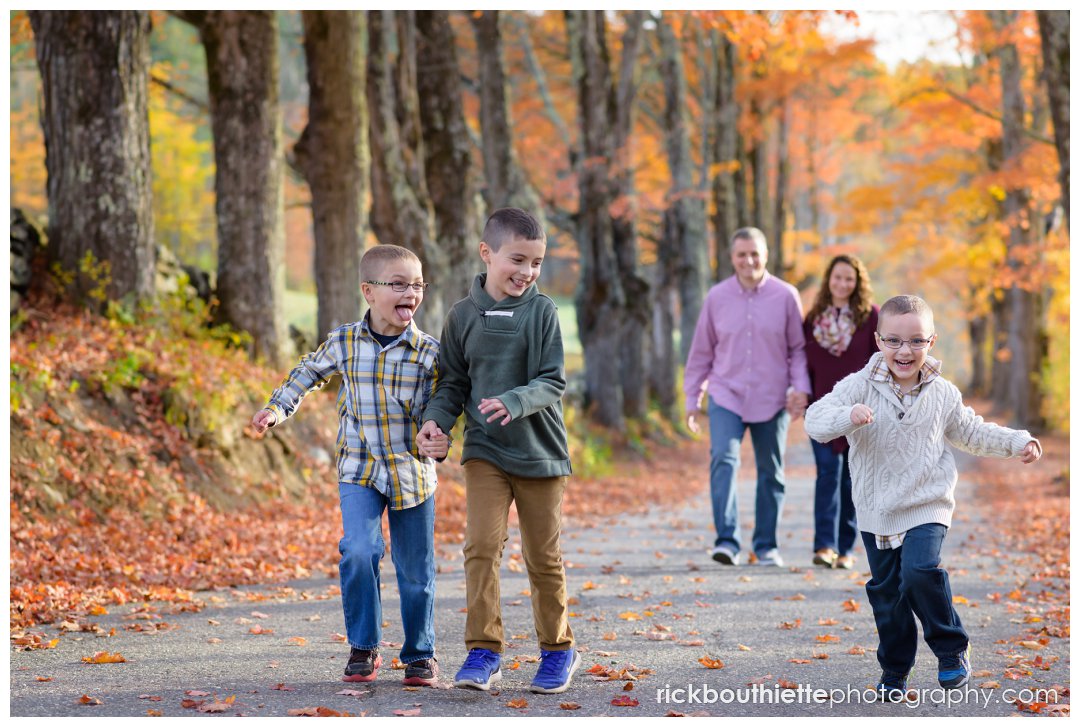 family portrait photography - three boys running with parents in background