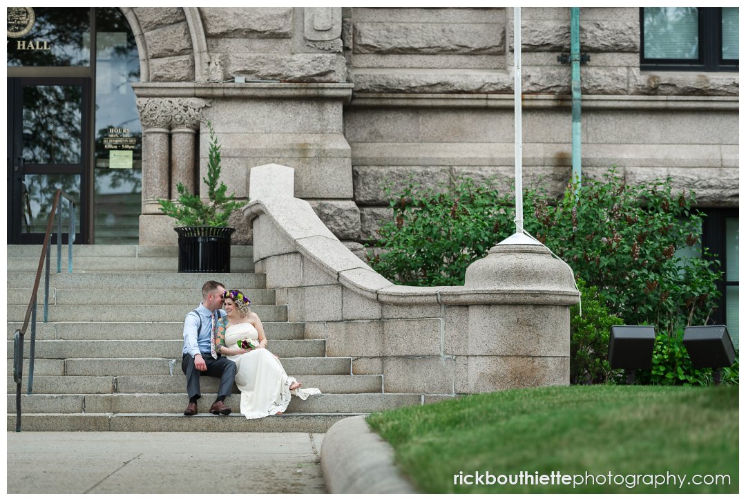 bride & groom sitting on stairs in front of lowell city hall